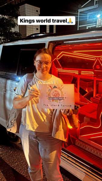 Customer with Kings World Transfer sign at night